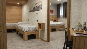 A room with three wooden beds, a wooden desk, and a mirror. - B&B Corte Rossa (Tirano)