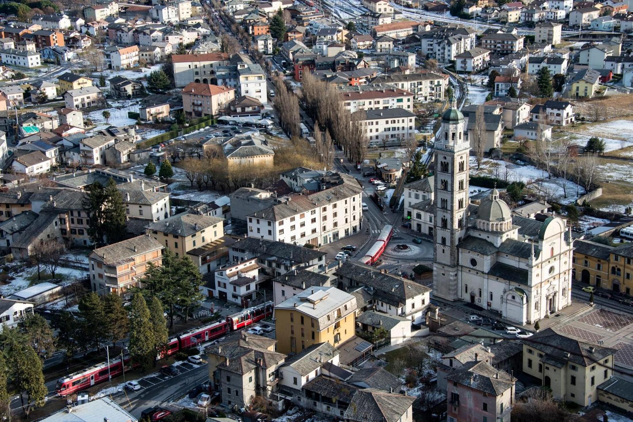 Vista aérea de una ciudad con una iglesia destacada y un tren rojo.