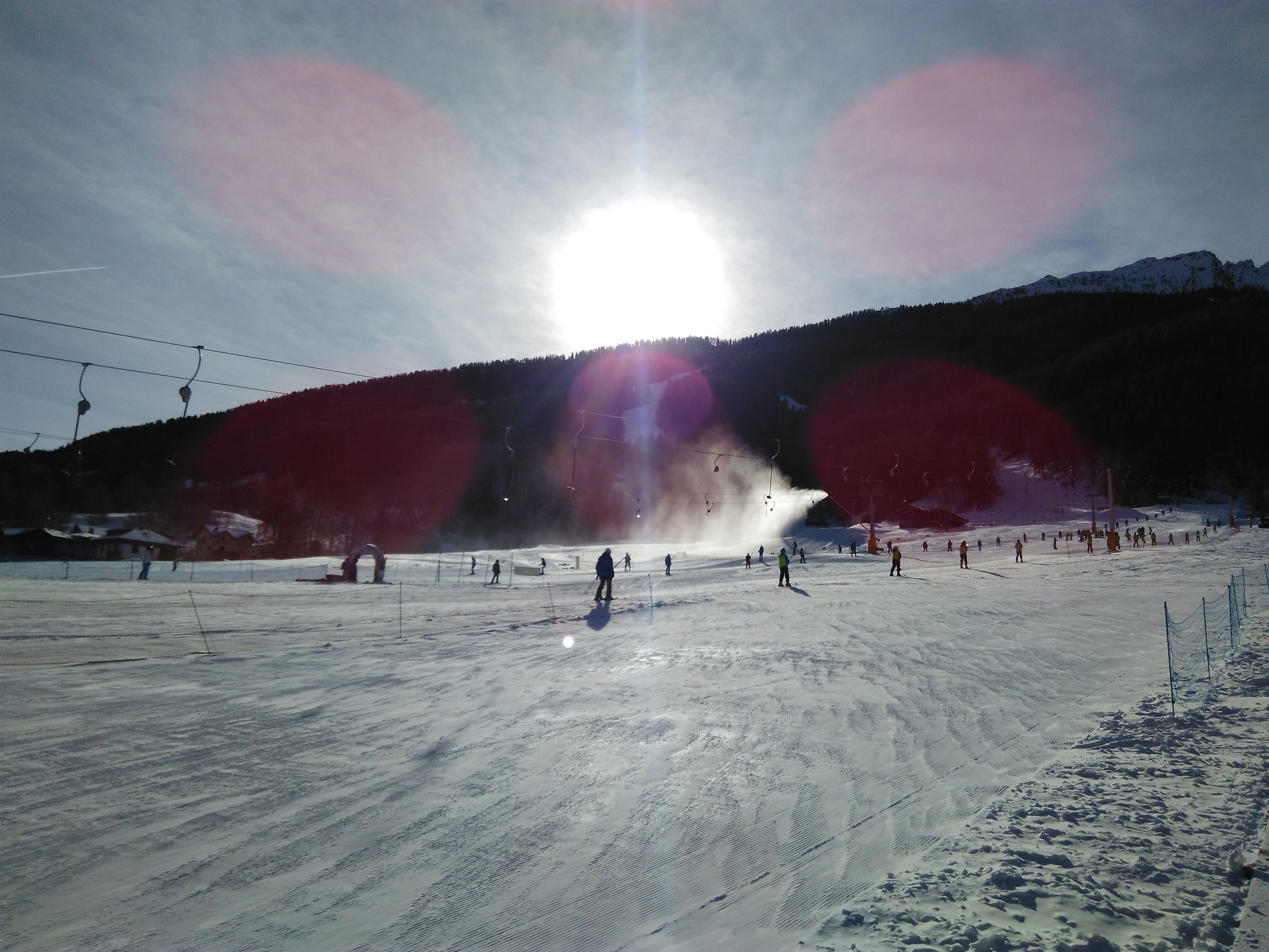 A ski resort with a ski lift, snow-covered slopes, and a clear sky.