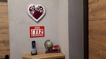 Eine Wand mit Herz-Dekoration, einem roten Feueralarm, einem Festnetztelefon, einem Globus und einer kleinen roten Kiste.