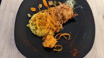 A black plate with a food dish, possibly a fried item, and some vegetables.