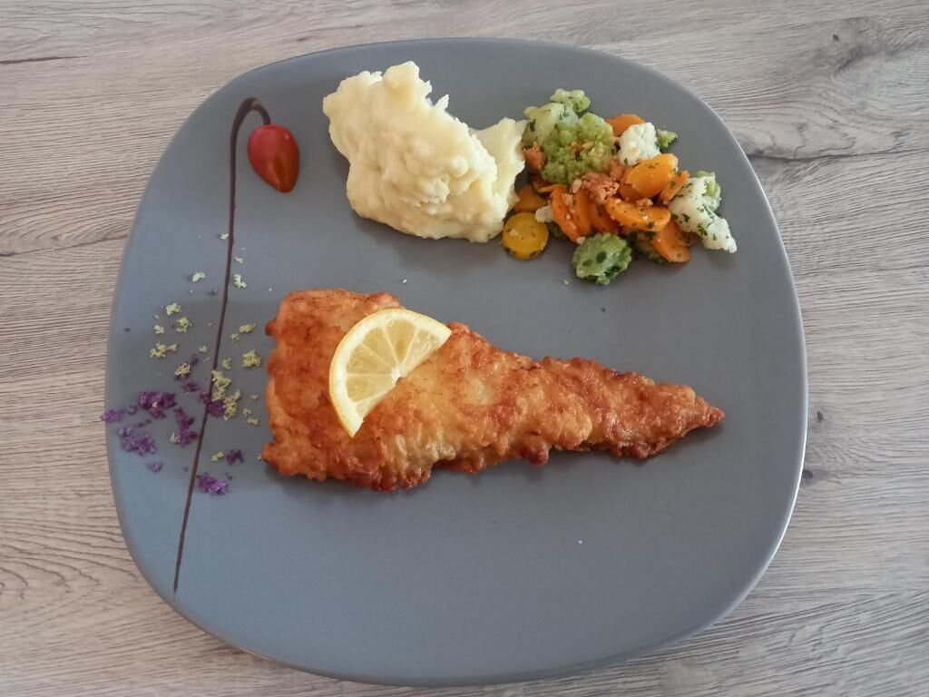 A plate with a breaded and fried item, mashed potatoes, and a vegetable medley.