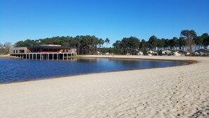 A beach with a modern building with a wooden deck and a pool. - L'Hôtel du Lac (Casteljaloux)