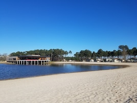 Uma praia com um edifício moderno, deck de madeira e piscina.