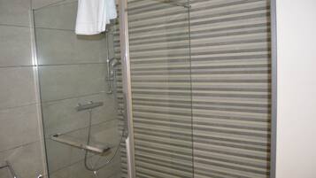 A shower with a glass door and a striped privacy screen.