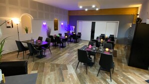 A modern dining area with multiple tables and chairs, a patterned floor, and recessed ceiling lighting. - L'Hôtel du Lac (Casteljaloux)