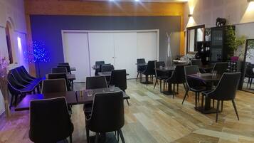 A conference room with multiple tables and chairs, a whiteboard, and a door in the background.