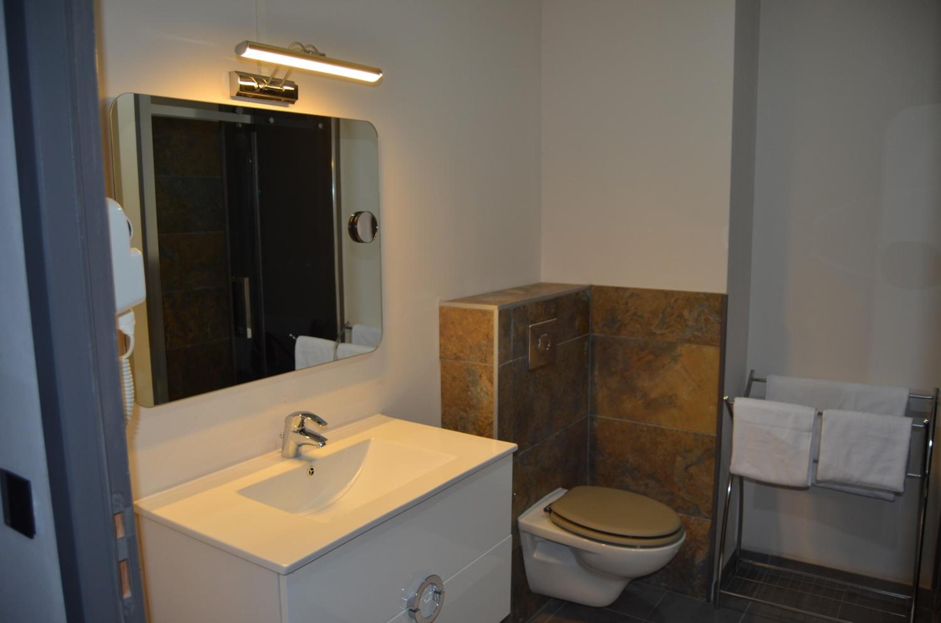 Een badkamer met een wit wastafel, een spiegel, een toilet en een douchegedeelte.