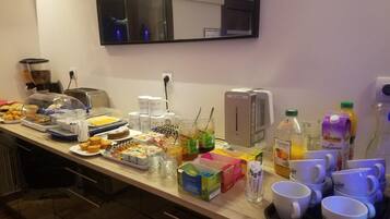 A breakfast buffet with various food items, beverages, and a coffee machine.