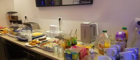 A breakfast buffet with various food items, beverages, and a coffee machine.