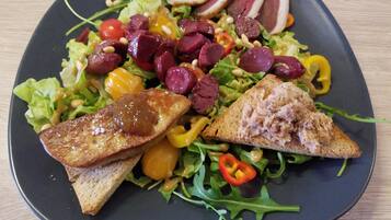 A plate with a salad, slices of meat, and two pieces of toasted bread.
