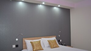A hotel room with a large bed, two bedside tables, a nightstand, and a wall-mounted lamp. - L'Hôtel du Lac (Casteljaloux)