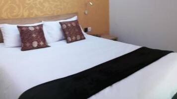 A hotel room with a bed, a TV, a desk, and a chair.