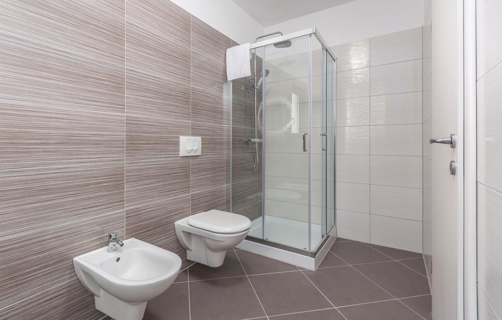 Ein modernes Badezimmer mit einem Bidet, einer Toilette und einer Duschkabine.