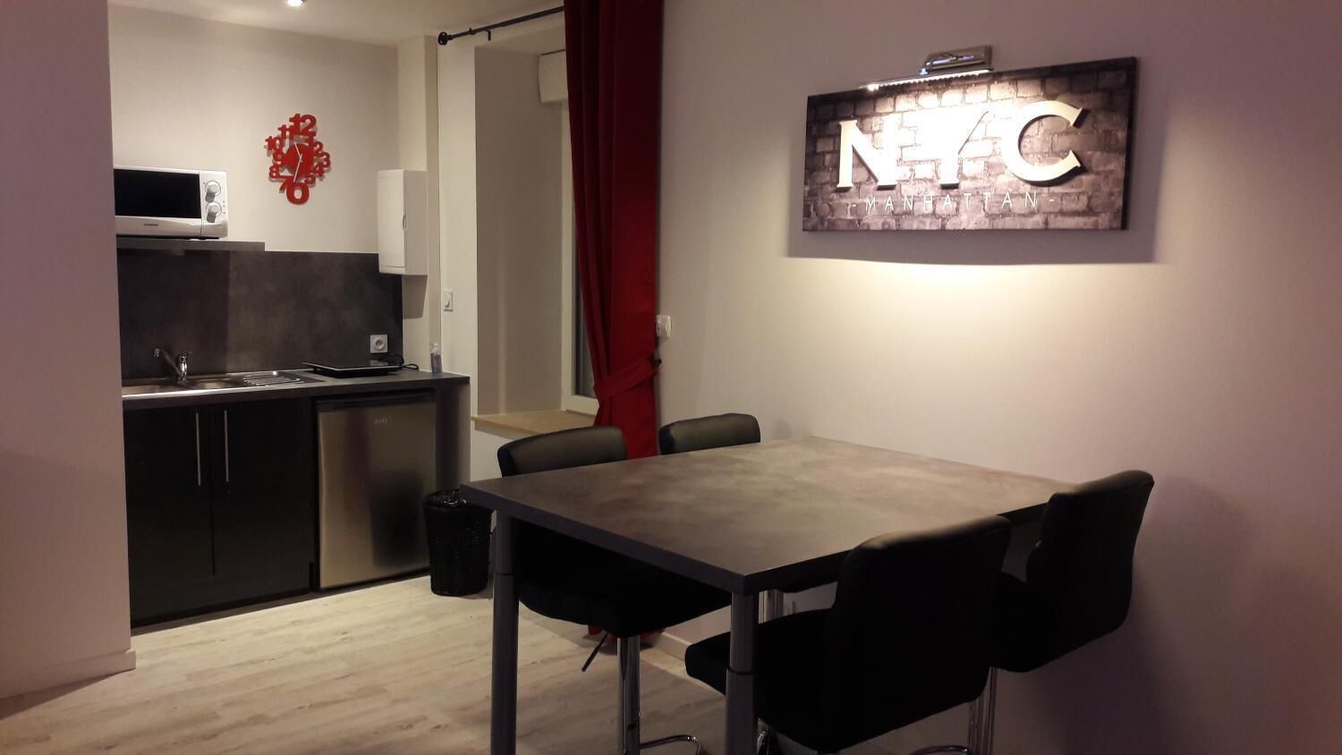 A compact kitchen with a microwave, cabinets, and a dining area with a table and chairs.
