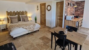 A bedroom with a bed, bedside tables, and a dining area with a table and chairs. - Au fer à cheval (Gandelain)