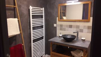 A bathroom with a towel rack, a mirror, a sink with a black basin, and a tiled backsplash.