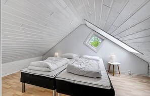 Cozy attic retreat with a single bed, bedside tables, and a small window.