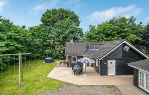 Enjoy a relaxing stay in this two-story home surrounded by lush greenery and trees, featuring a hot tub and covered patio area.