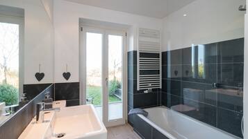 A modern bathroom with a large bathtub, a separate shower area, and a vanity with a sink.