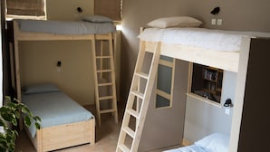 Un dormitorio tipo residencia con literas, una escalera y una estantería.