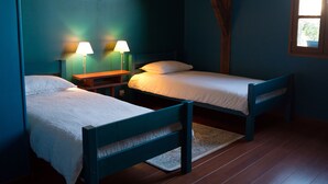 Una habitación con dos camas, una mesita de noche y dos lámparas.