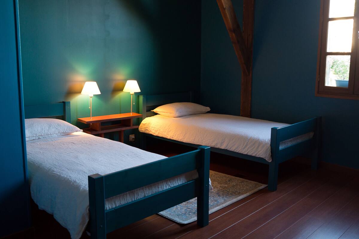A room with two beds, a nightstand, and two lamps.