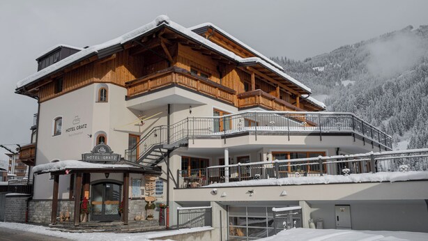 Un hotel con fachada de madera, balcones y un cartel que dice 'HOTEL GRATZ'.