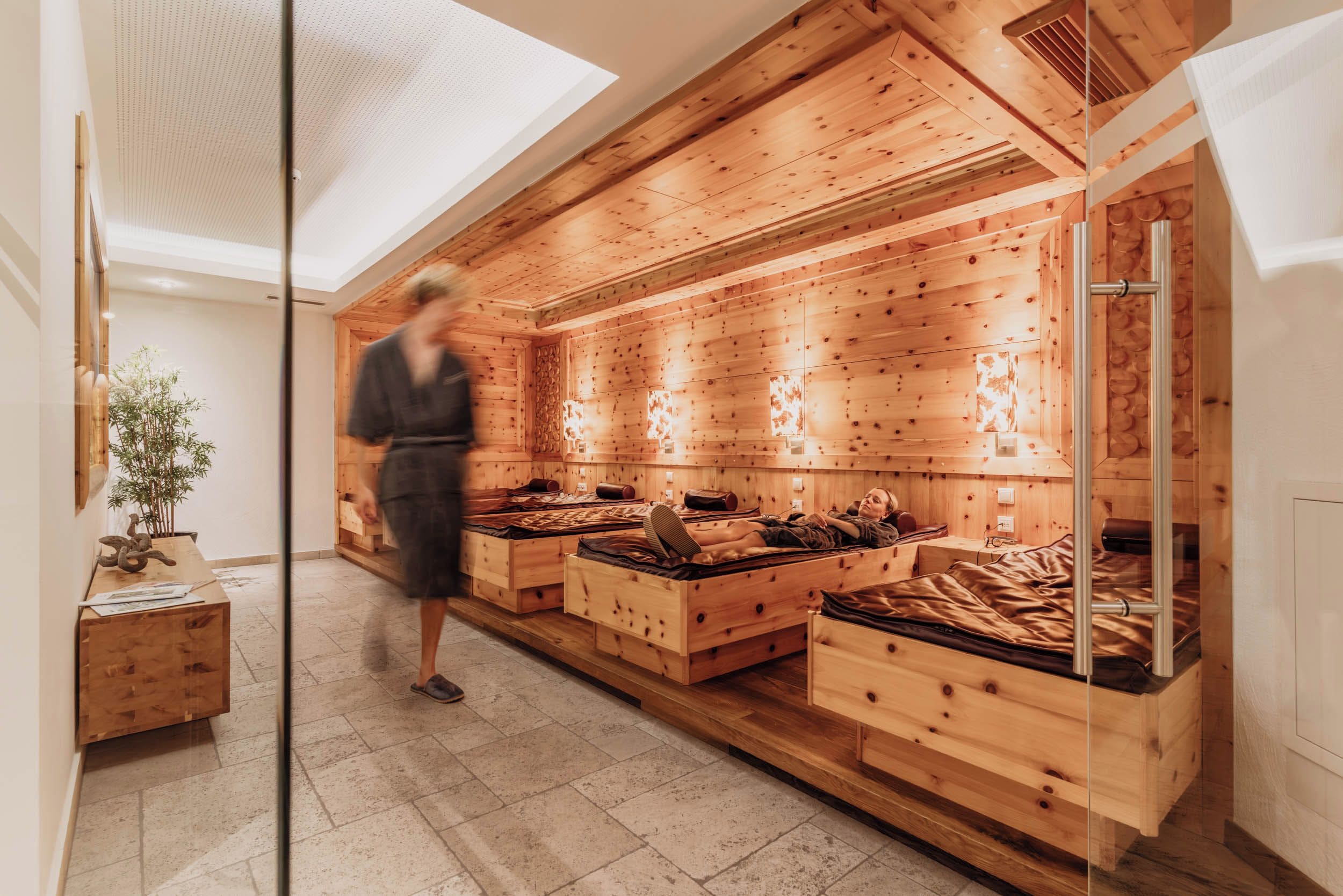 Un cuarto de spa con paredes de madera, varias camas y una pared de vidrio.