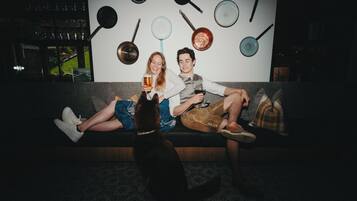 A room with a couch, a dog, and a wall with hanging cookware.