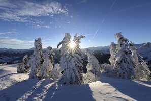 A snowy mountain landscape with a clear sky and a visible sun. - Hotel Ziach & Candy (Grossarl)