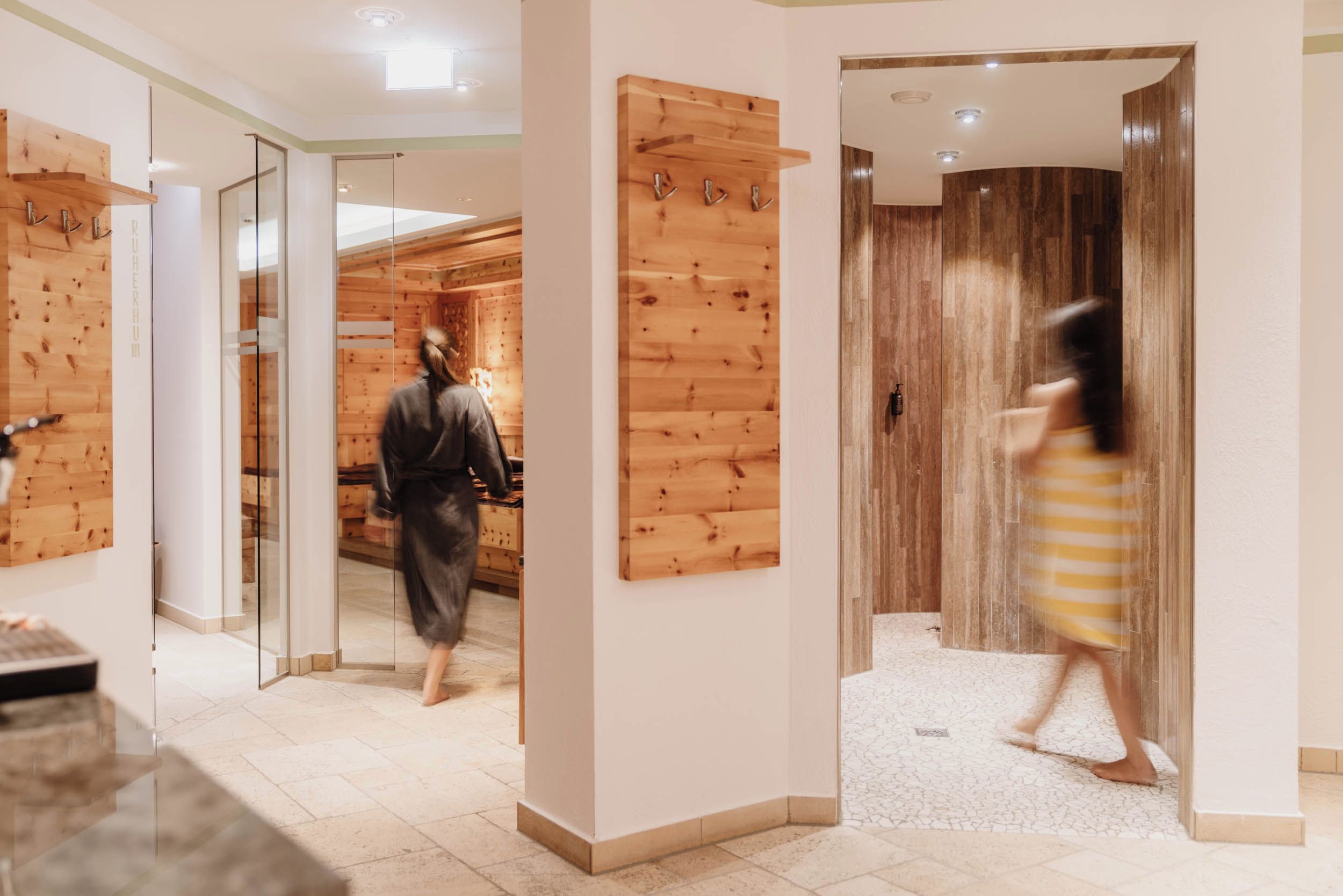 Un pasillo de hotel con paneles de madera, una puerta de cristal y piso de baldosas.