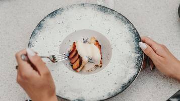 A person holding a plate with a dessert, using a fork.