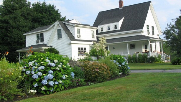 A large, two-story house with a prominent porch and a well-maintained garden. - Bittersweet Bed and Breakfast (York Beach)