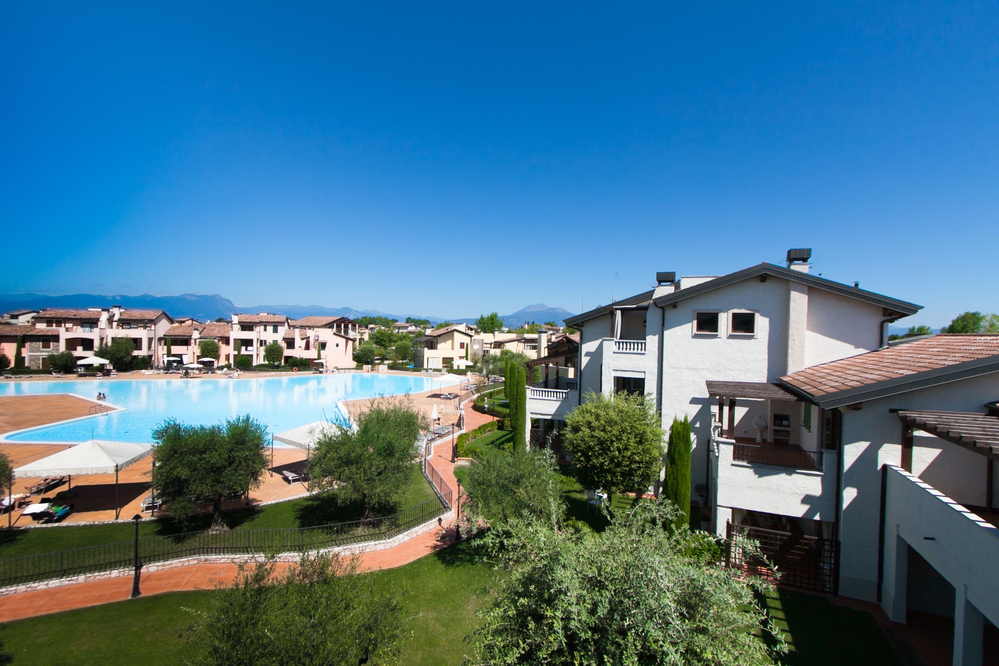 A resort with a swimming pool, multiple buildings, and a clear view of the mountains in the background.