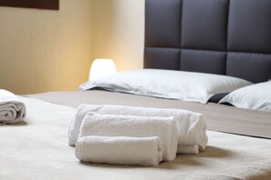 A neatly made bed with white linens and a dark headboard. - Lugana Village Resort & Sporting Club (Peschiera del Garda)