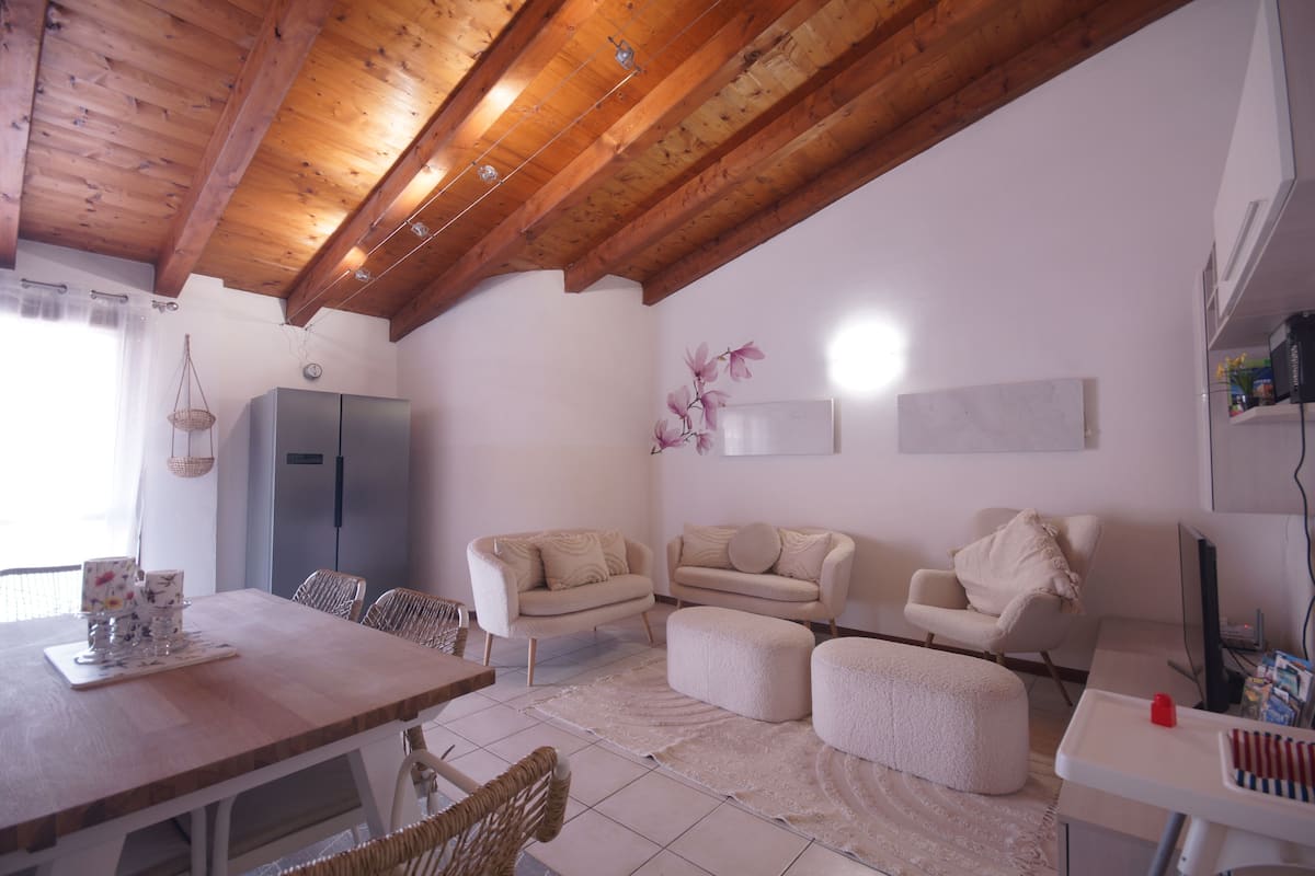 Un salon avec un plafond en bois, un coin repas avec une table et des chaises, et un ensemble de canapés.