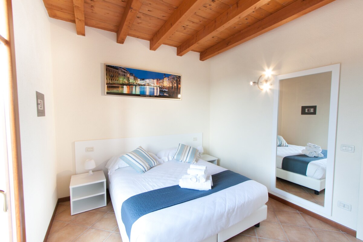 Une chambre d’hôtel avec un lit, une table de chevet, un miroir et un tableau au mur.