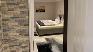 A bedroom with a bed, a stone wall, and a painting on the wall. - Apartment Ahsbahs Suite near Airport (Elskop)