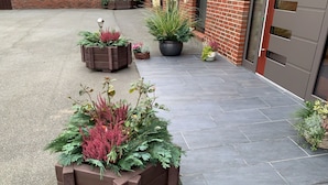 A paved walkway with potted plants and a brick wall. - Apartment Ahsbahs Suite near Airport (Elskop)