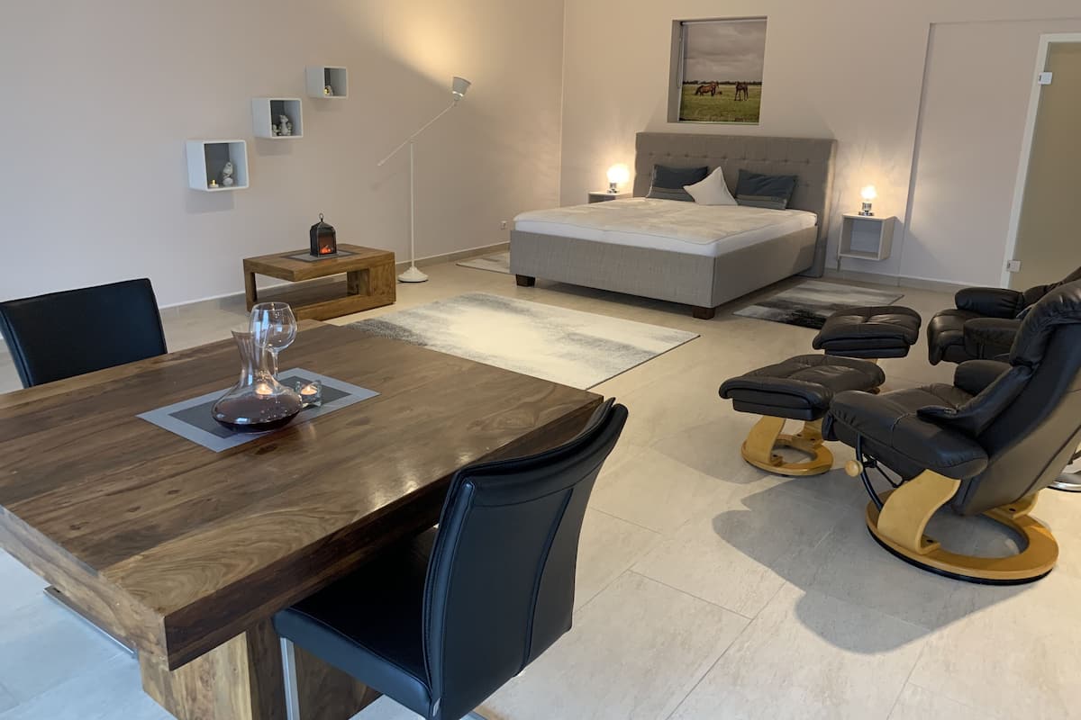 A modern bedroom with a bed, bedside tables, a desk, and a massage chair.