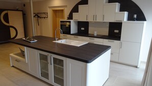 A modern kitchen with white cabinetry, a black countertop, and a built-in sink. - Apartment Ahsbahs Suite near Airport (Elskop)