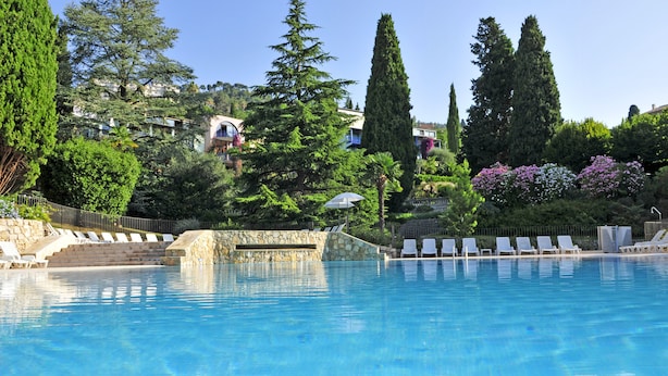 Une piscine avec des chaises longues et un mur en pierre.