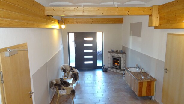 A hallway with a fireplace, wooden walls, and a tiled floor.