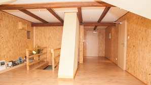 Una habitación con paredes y suelos de madera, una escalera de madera y un portal al final.