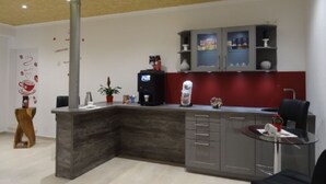 Una cocina moderna con encimera oscura, una cafetera y un salpicadero rojo.