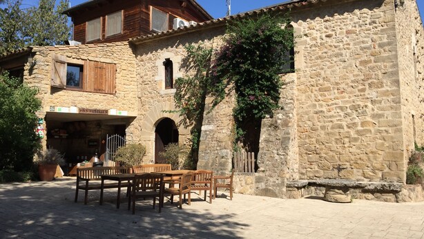Un edificio de piedra con muebles de madera afuera.