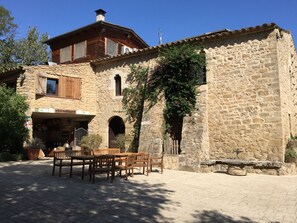 Un edificio de piedra con muebles de madera afuera.