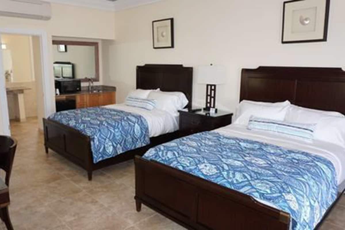A hotel room with two single beds, a desk, and a chair.