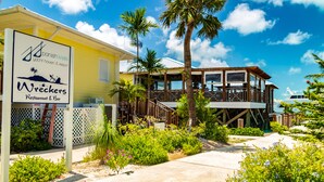 A waterfront restaurant with a deck and outdoor seating, surrounded by lush greenery and palm trees. - Spanish Wells Yacht Haven (Spanish Wells)